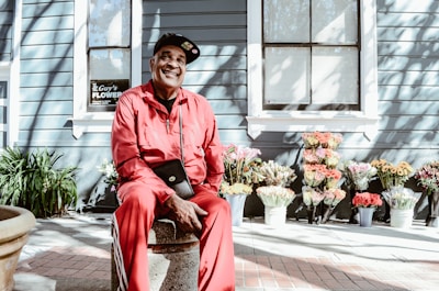 man sitting on concrete stool near teal building during daytime