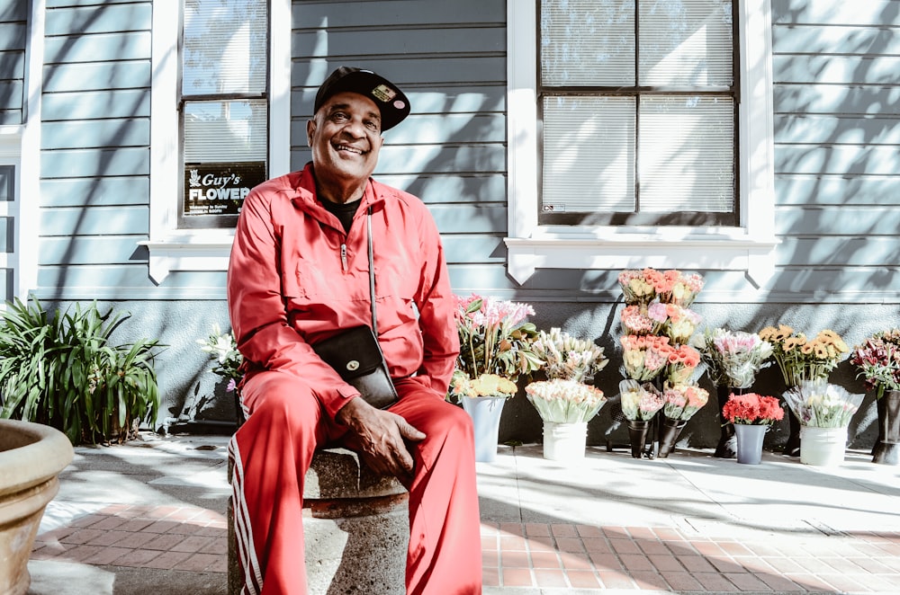 man sitting on concrete stool near teal building during daytime