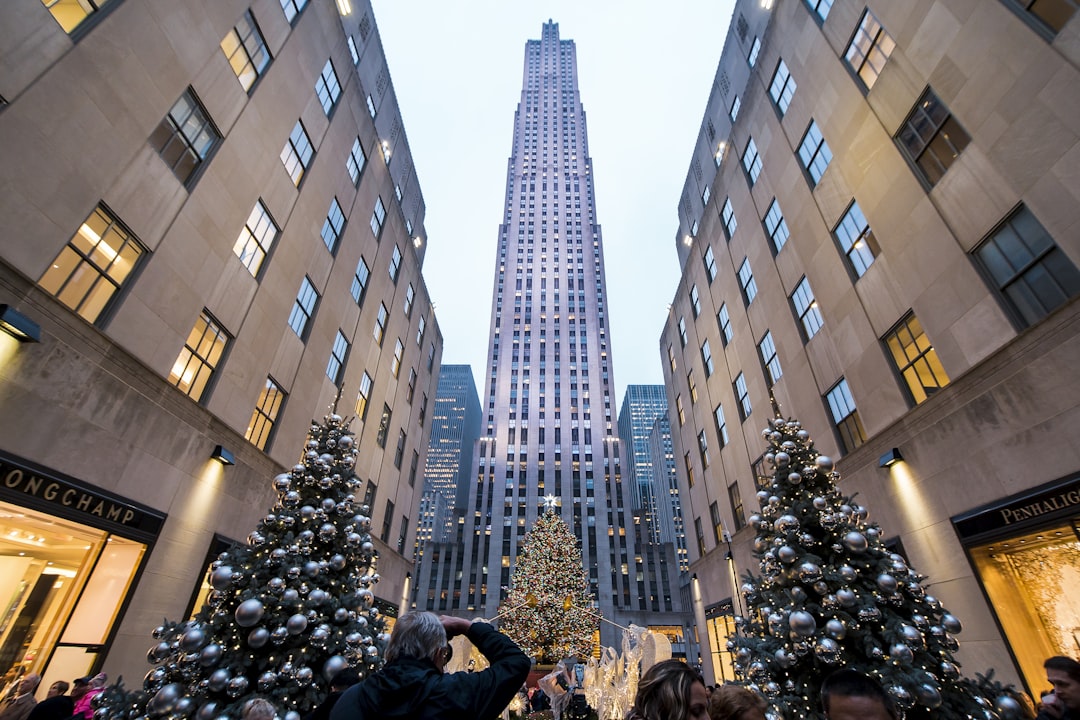 person standing beside two Christmas trees with baubles, Christmas by Rockefeller Center