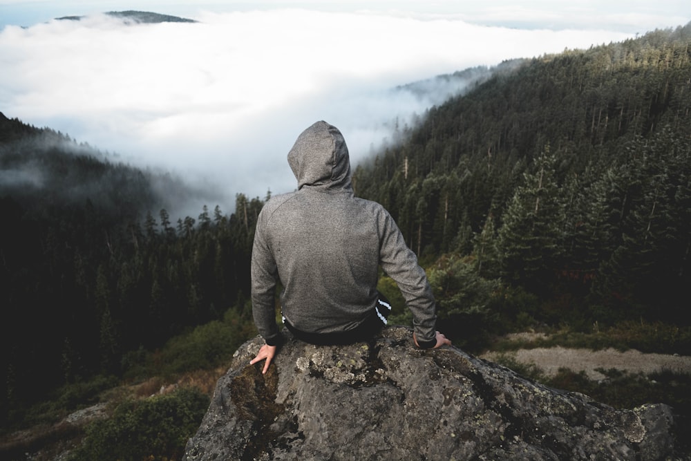 man sitting on hill in forest