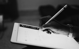 person typing by Apple Pencil on iPad in a room