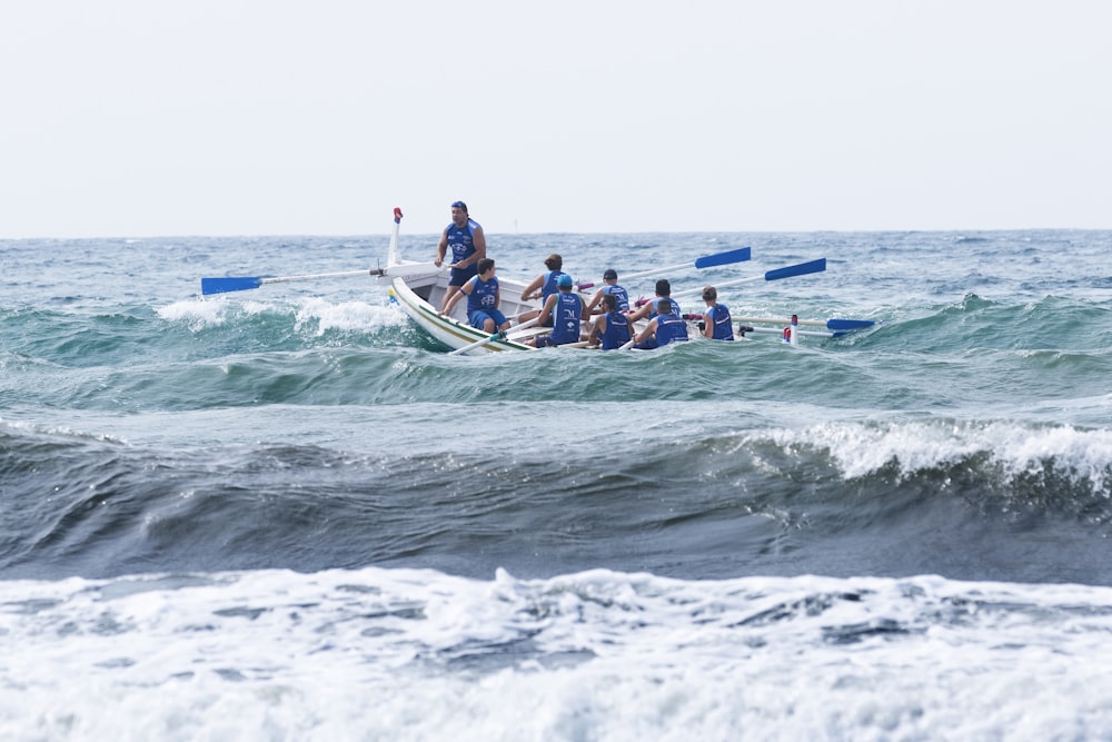 昼間に激しい波でボートを漕ぐ男性のグループ