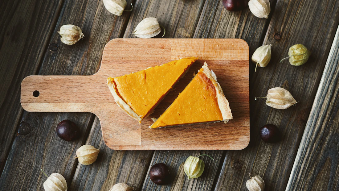 Two sliced orange custard pies on a wooden board