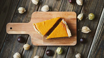 Two sliced orange custard pies on a wooden board