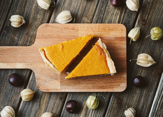 two sliced pies on brown wooden chopping board