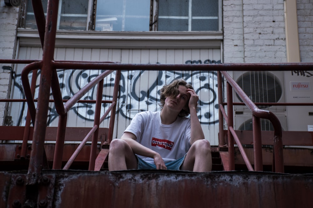 man sitting on red steel stairs during daytime