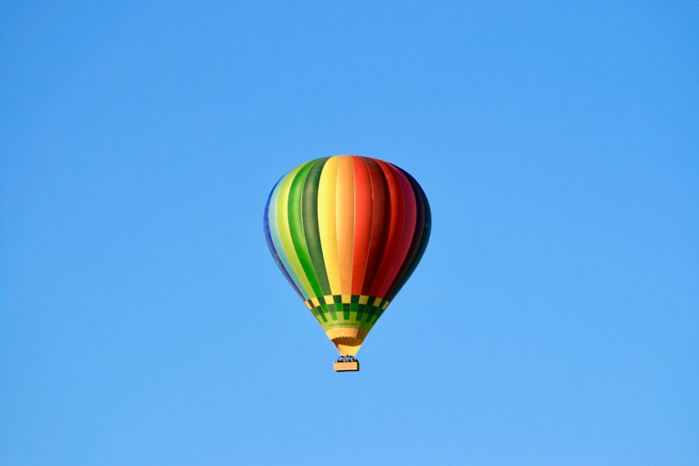 low angle photo of multicolored hot air balloon flying under blue skty