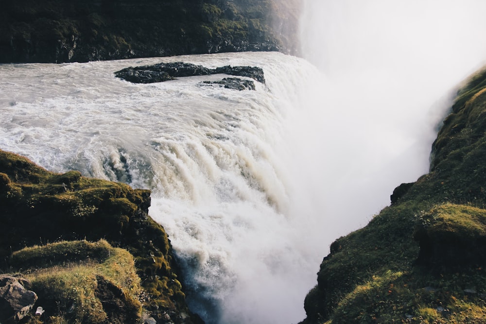 waterfalls surrounded by hills daytime