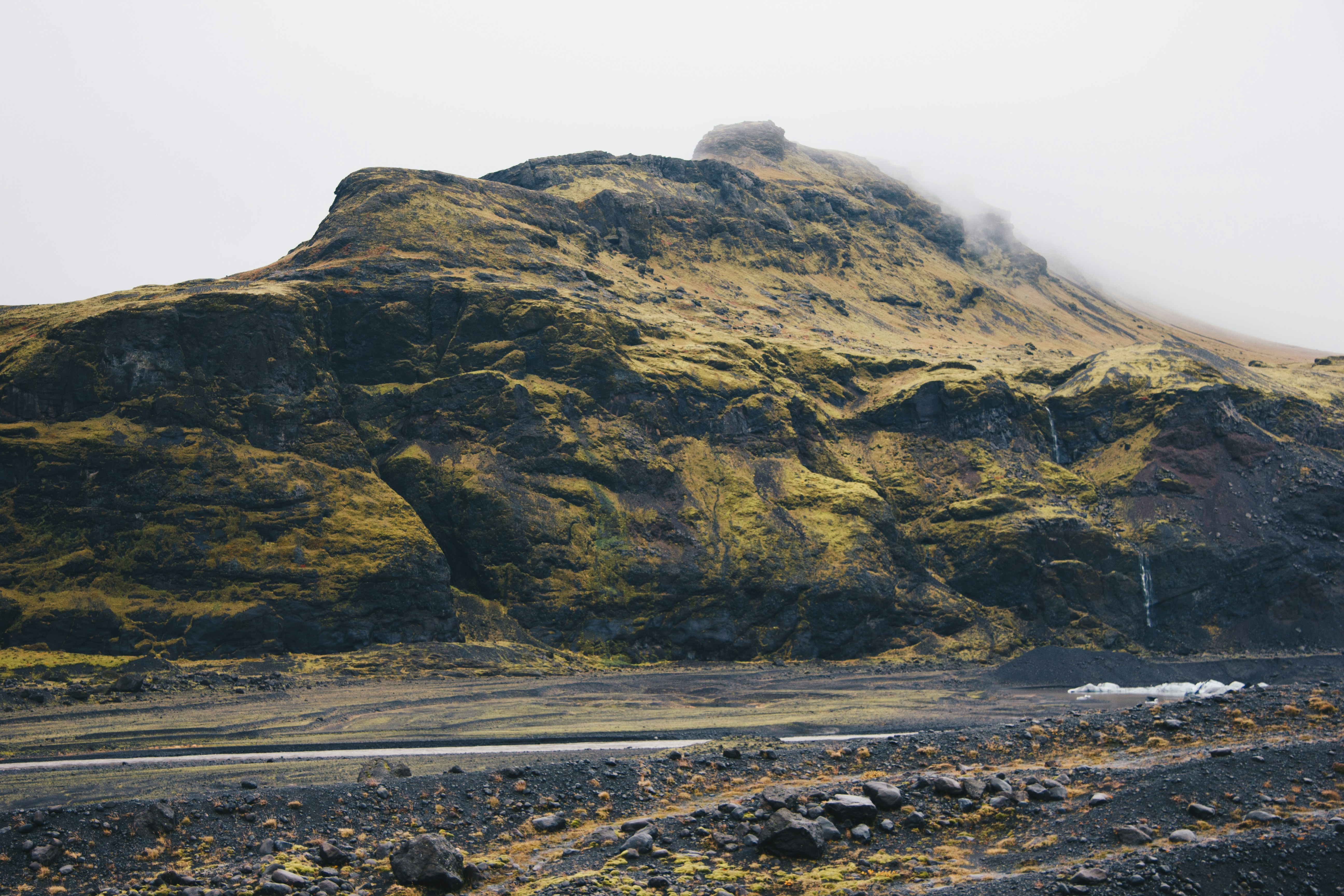 Misty Nordic mountain landscape at dusk, volcanic terrain, deep shadows, low atmospheric fog