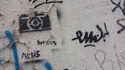 Close-up of a black and gold stencil design sprayed on a textured urban wall.