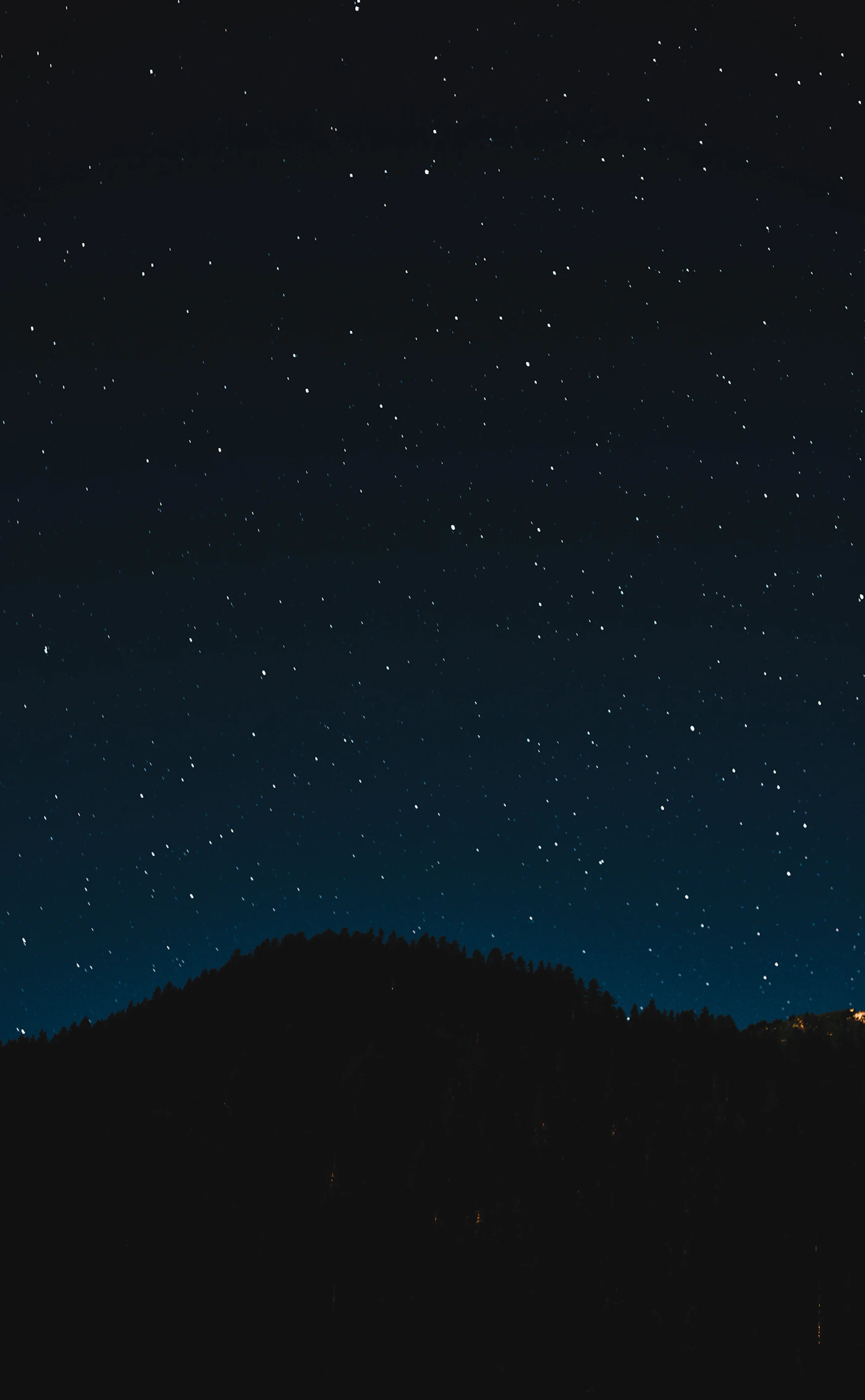 Starry night sky over a mountain silhouette