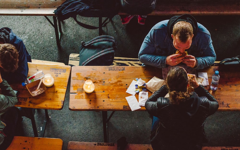 man and woman eating sandwich infront of table