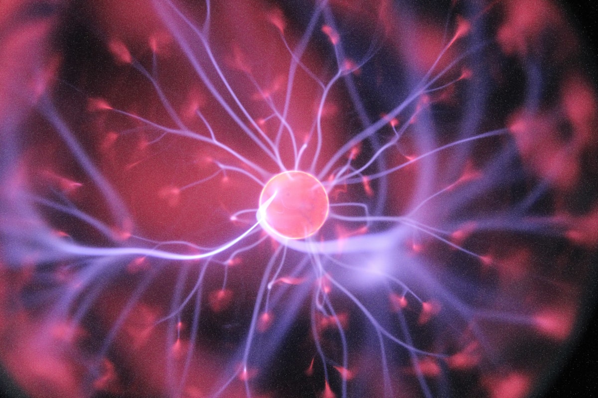 Pink neuron with pink and purple electrical pulses emerging from i