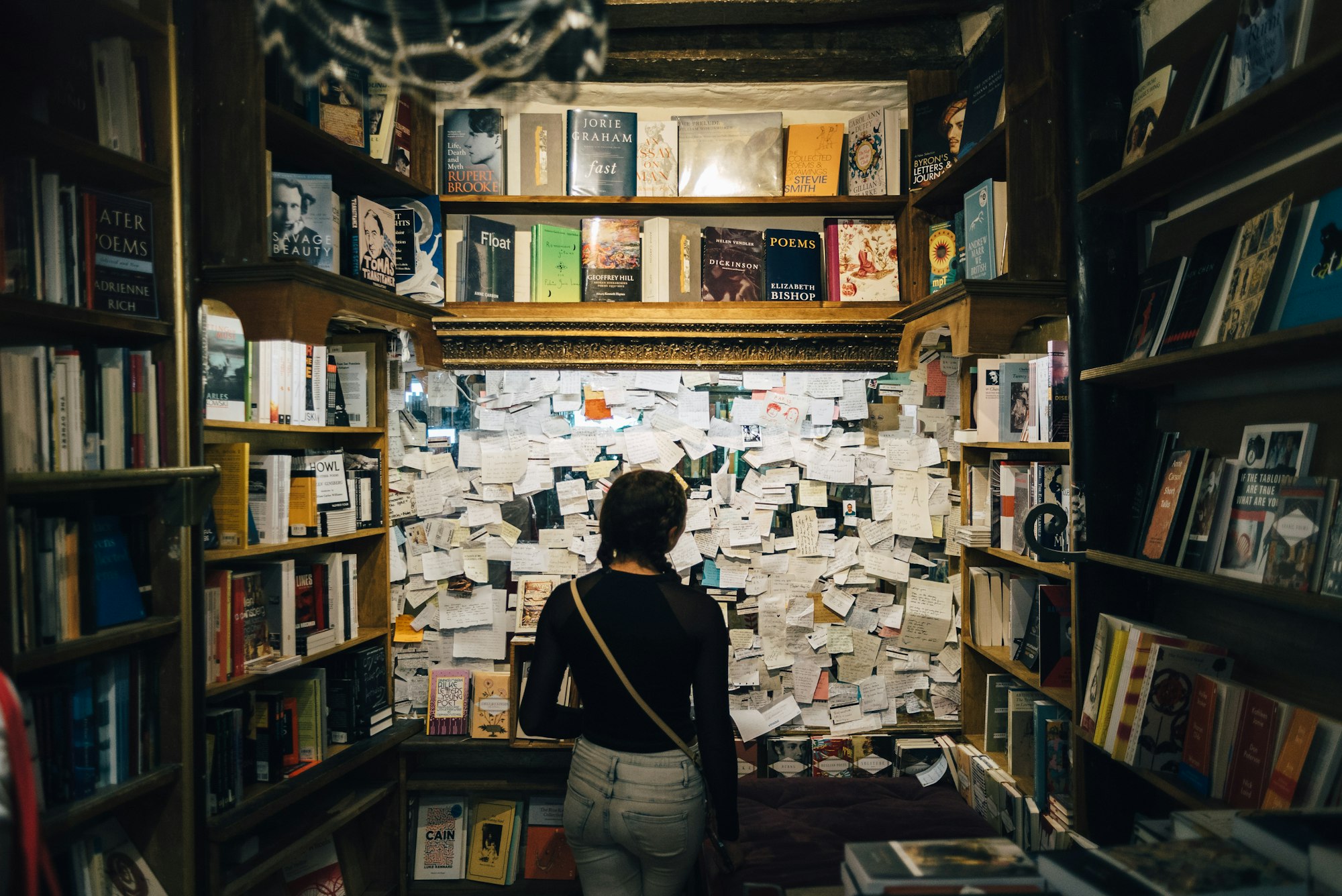 Une personne regardant un mur où sont accrochées de nombreuses feuilles de papier. 