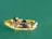 A small yellow boat on teal water with two people handling fishing nets while checking a bucket of fish. An outboard motor is attached at the back of the boat.
