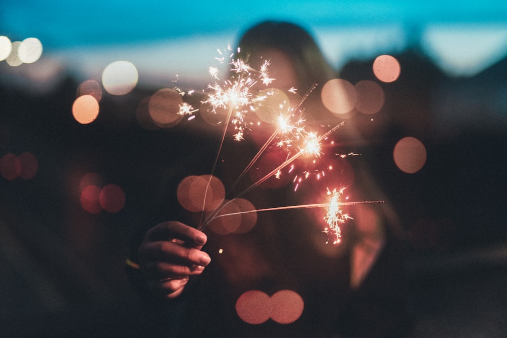 woman holding firework sticks in shallow photography