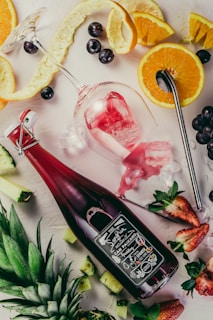 flat-lay photograph of sliced fruits, swing top bottle, and wine glass