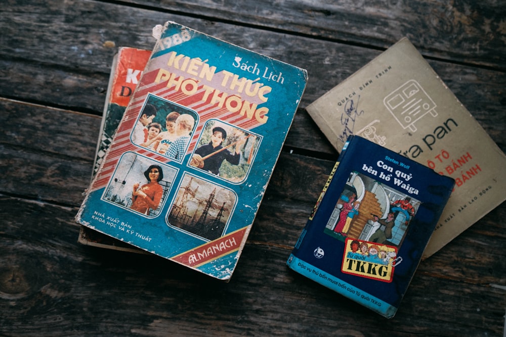 four assorted-title books on brown and black wood planks