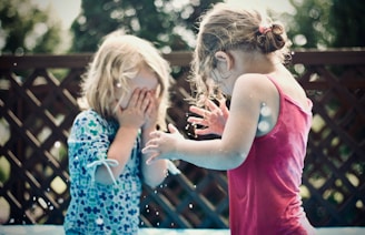 two children playing water during daytime shallow focus photography