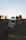 Close-up of a man taking a photo with a smartphone in a park during sunset