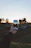 Close-up of a man taking a photo with a smartphone in a park during sunset