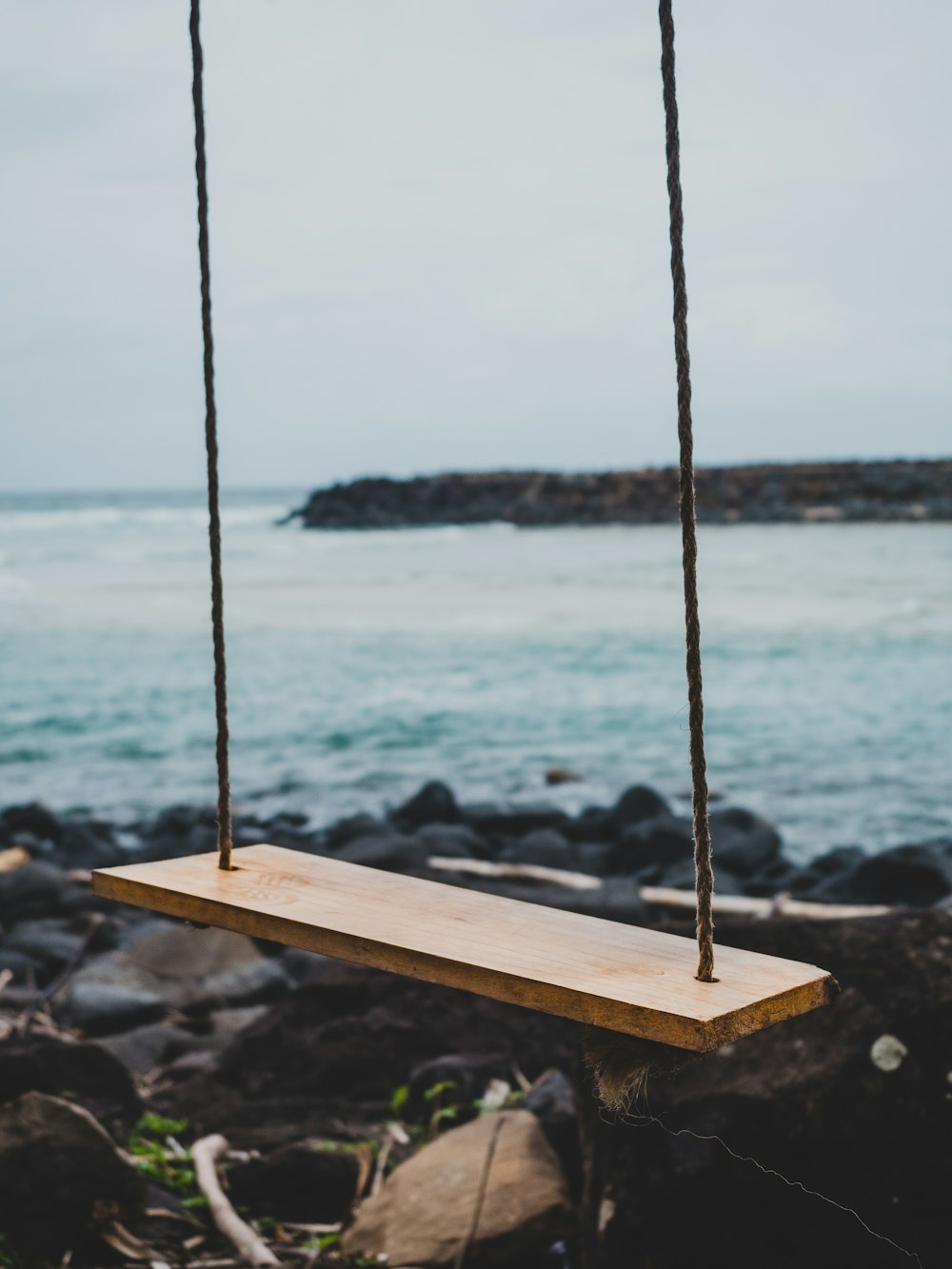 brown wooden swing chair beside shoreline