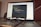 A laptop is open and displaying a programming interface with code written in a text editor. A pair of eyeglasses is placed on the keyboard in front of the laptop, creating a blur effect over the lower part of the screen.