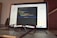 A laptop is open and displaying a programming interface with code written in a text editor. A pair of eyeglasses is placed on the keyboard in front of the laptop, creating a blur effect over the lower part of the screen.