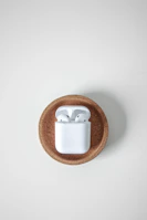 Compact wireless earbuds in their charging case, set on a marble surface.