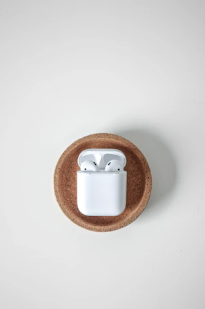 Compact wireless earbuds in their charging case, set on a marble surface.