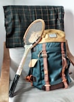vintage brown tennis racket and green hiking backpack