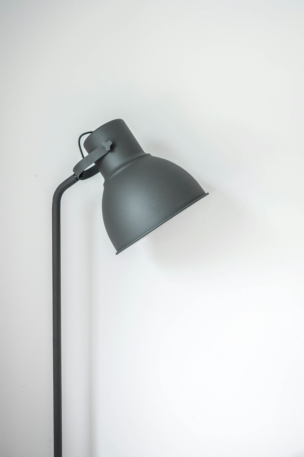 lampe de bureau grise près du mur blanc