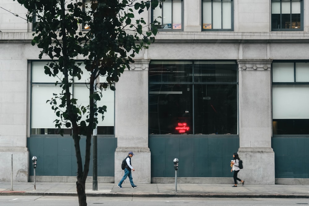 two man and woman walking near grey concrete building