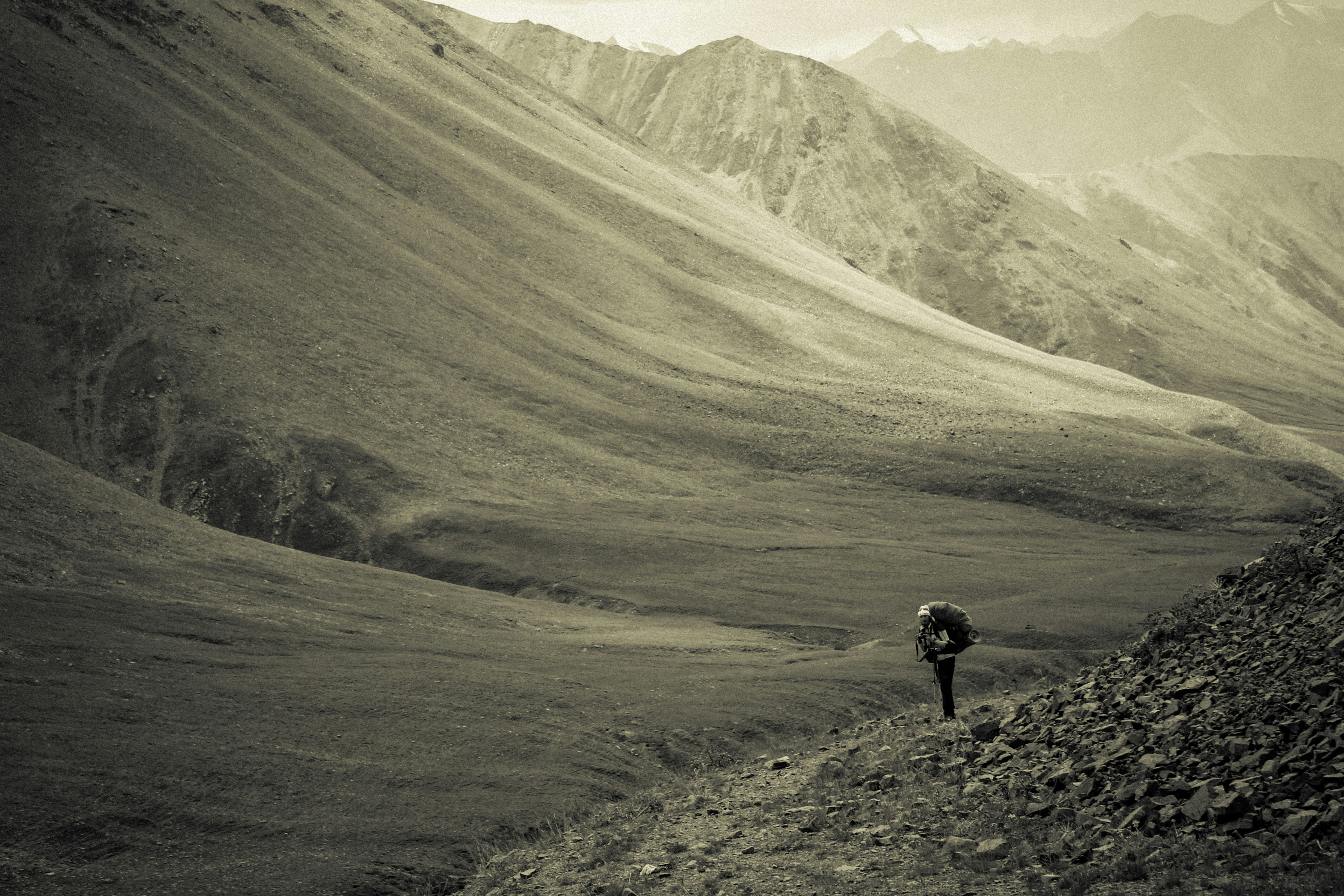 grayscale photo of person walking on mountain feet during daytime, Off the beaten path
