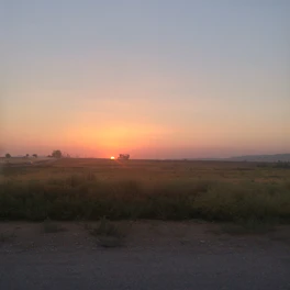 A serene landscape with an old man silhouetted against a sunset, completely unadorned.