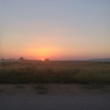 A serene landscape with an old man silhouetted against a sunset, completely unadorned.