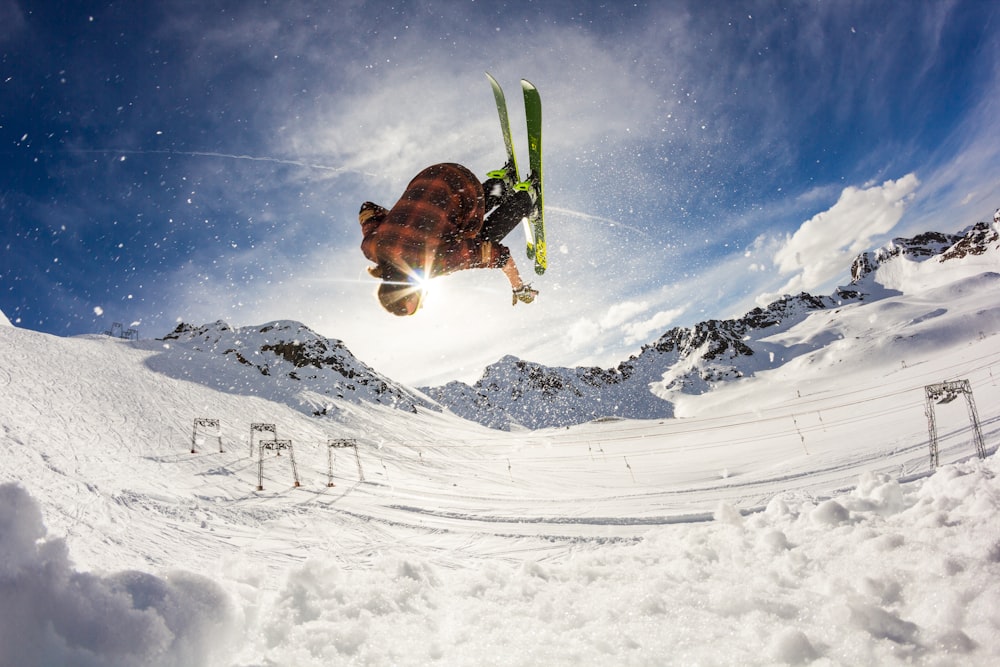 person flip skiing above snow during daytime