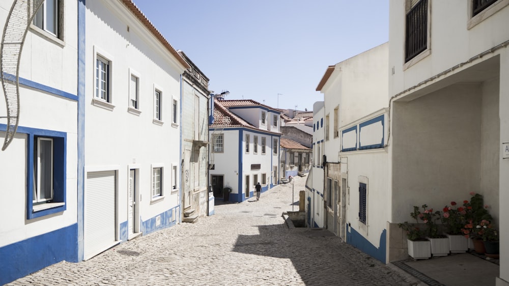 Route grise bordée de maisons en béton blanc et bleu pendant la journée