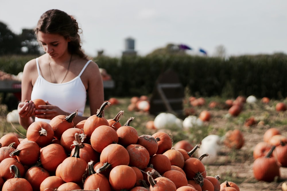 woman choosing from pile of pumpkins