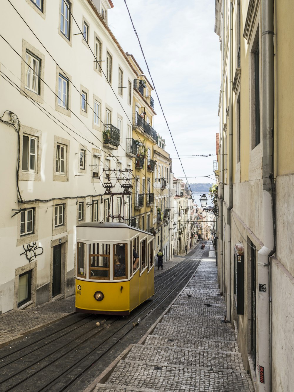 yellow and white bus in the middle of white buildings during daytime