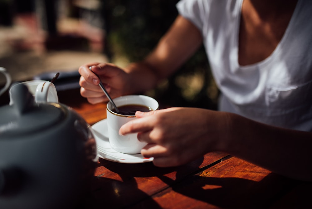 person holding white ceramic cup