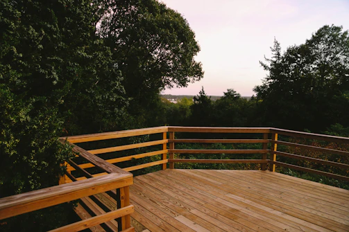 Wooden deck with fresh stain overlooking a lush forest setting.