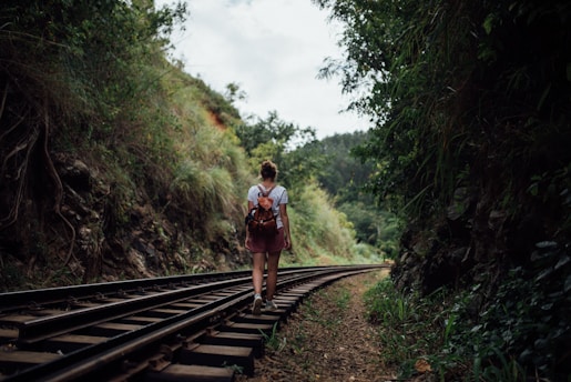woman walking on train trail at daytime