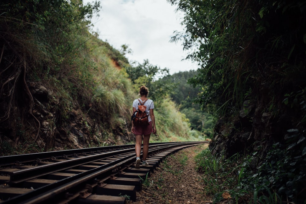 mulher que caminha na trilha do trem durante o dia