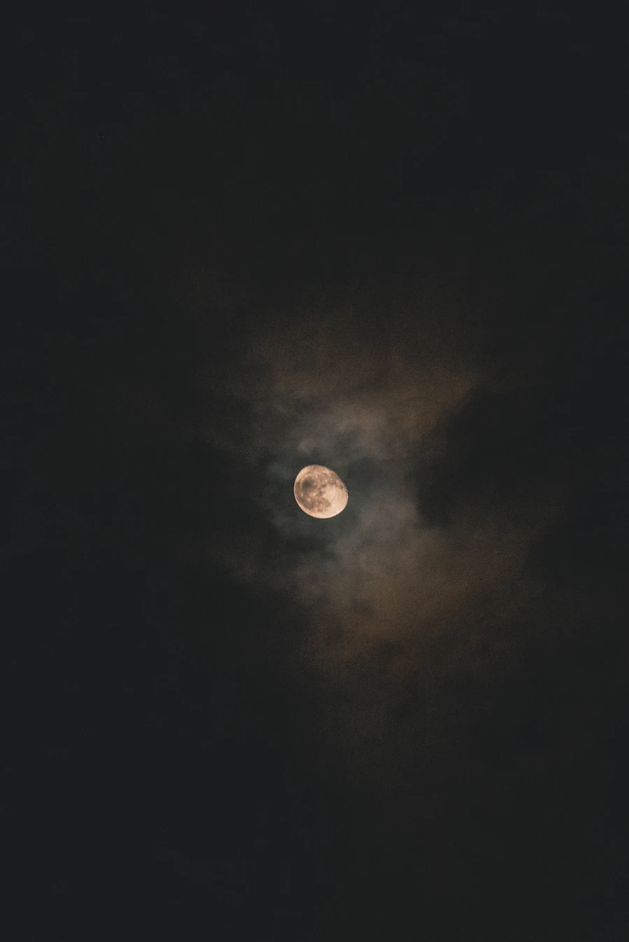 A bright moon behind dark clouds