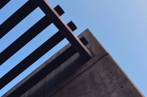 Photo of a modern construction site showcasing sleek architectural beams under a clear sky.