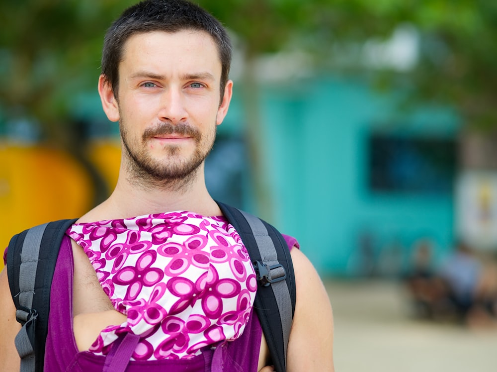 selective focus closeup photography of man in purple and white floral sleeveless shirt and black-and-gray backpack