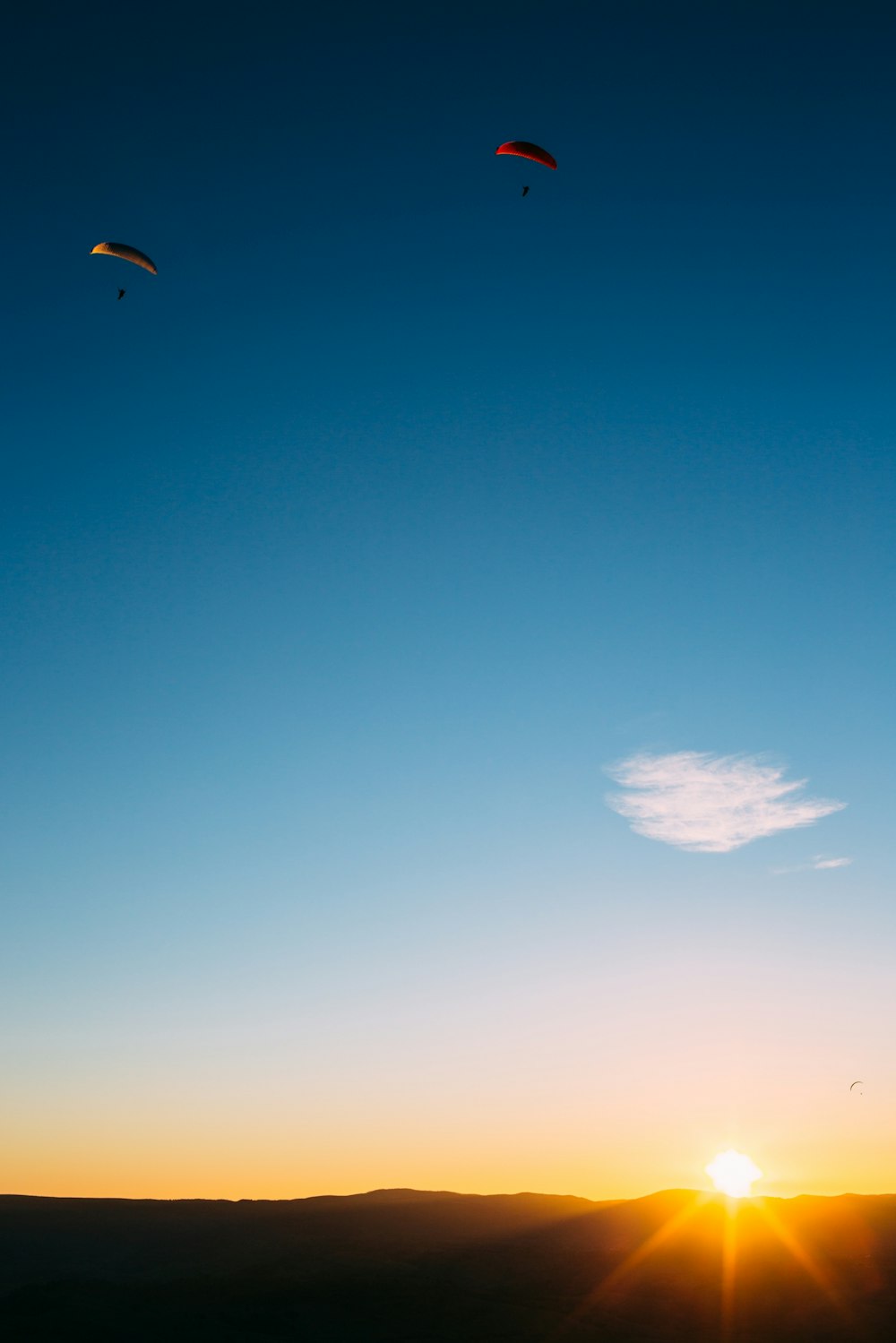 Dos personas haciendo parapente durante la hora dorada