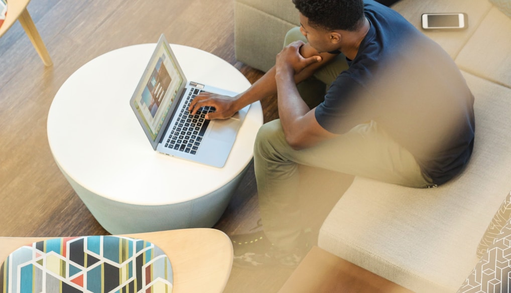 man sitting on couch using MacBook