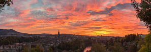 A panoramic view of the Amazon river at sunset, with vibrant orange and pink skies.